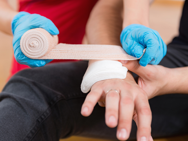 Illustration of someone giving first aid by applying a bandage to an arm